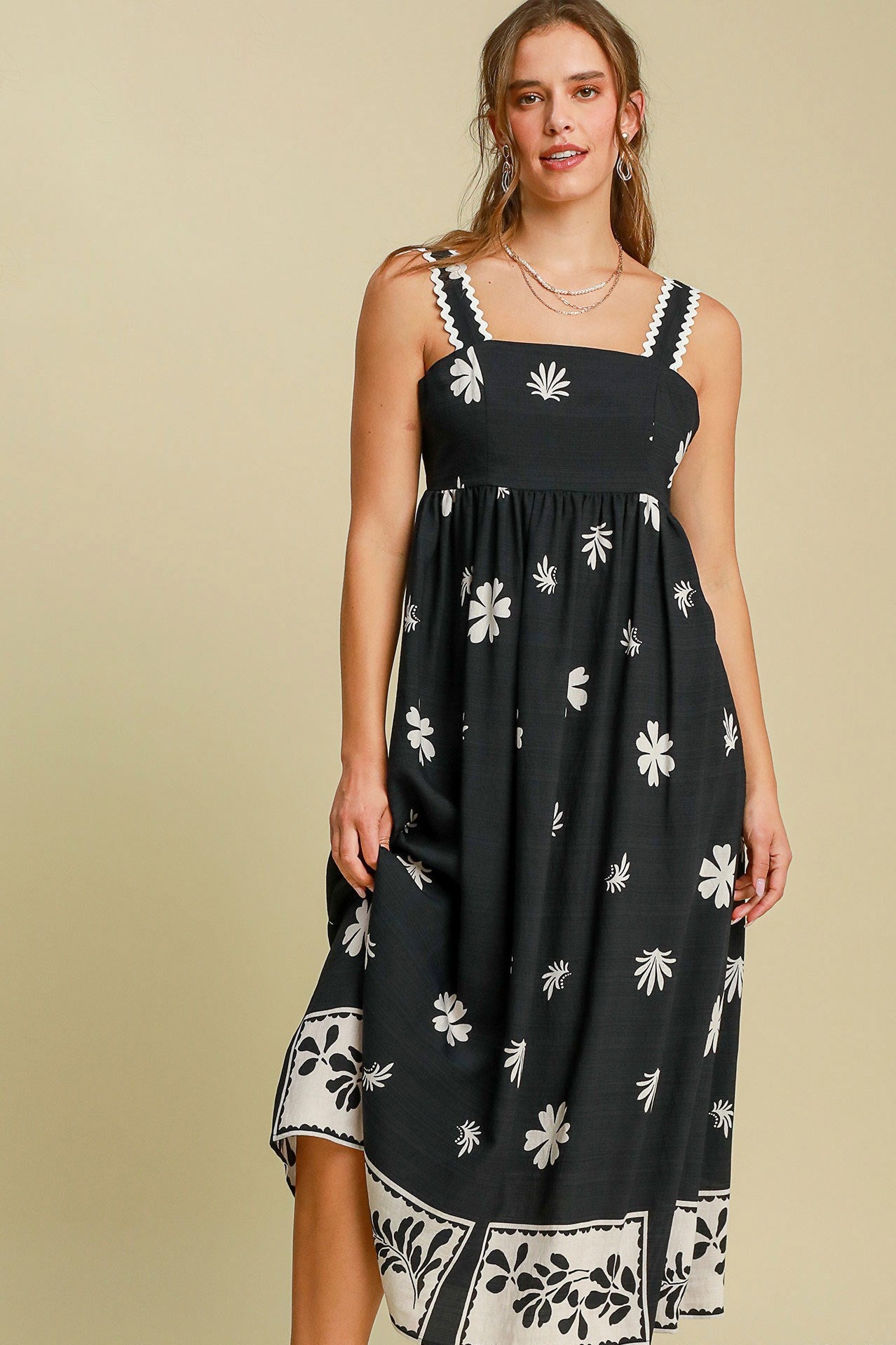 Woman wearing a black dress with white floral patterns on a beige background