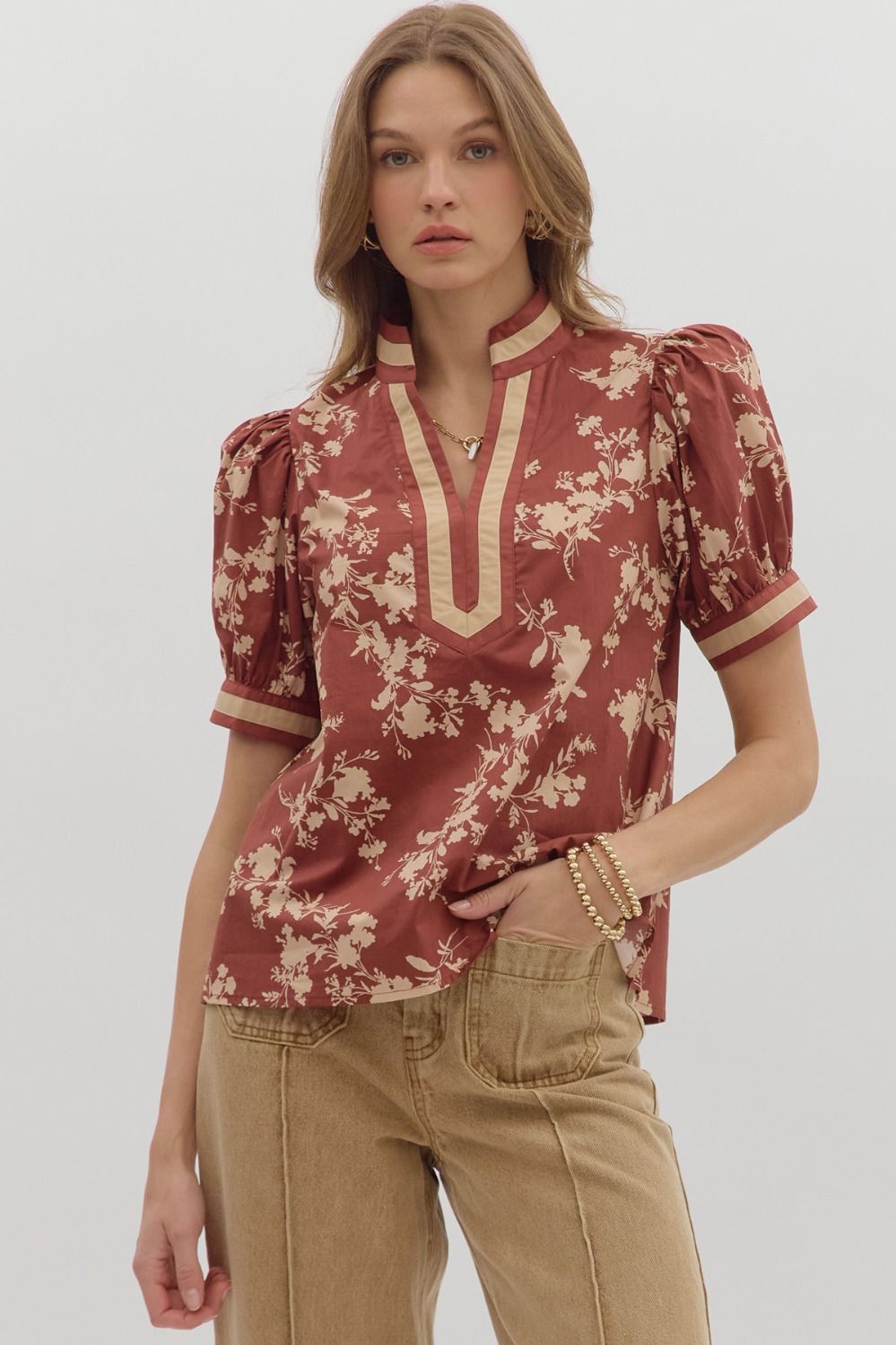 Woman wearing a floral blouse with puff sleeves on a plain background