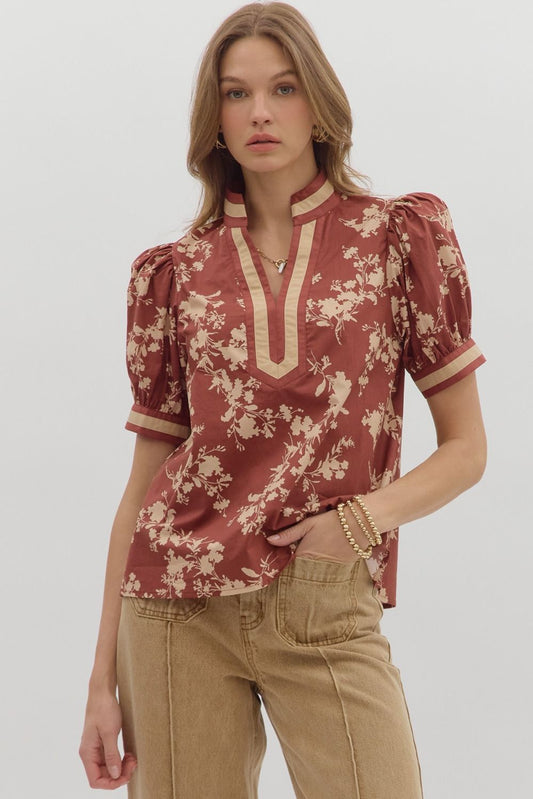 Woman wearing a floral blouse with puff sleeves on a plain background