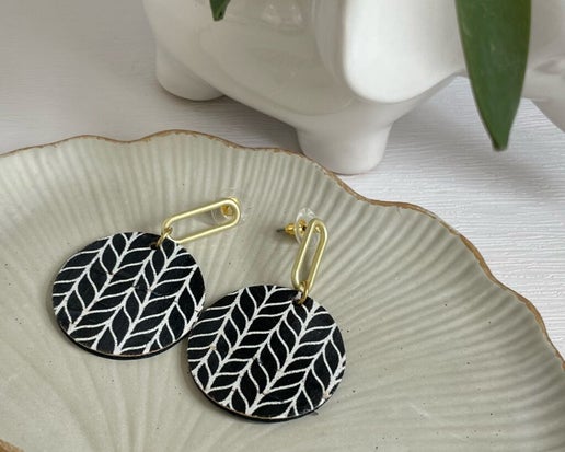 Barbara Earrings - Mindy's Boutique
These Barbara Earrings feature Black &amp; White Cork and Leather, complemented by Gold plated Brass oval posts. The design is both playful and sophisticated, making it a great addition to any outfit.