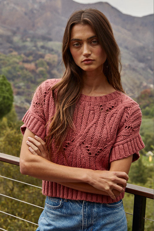 Woman wearing a pink knitted top with a mountainous background