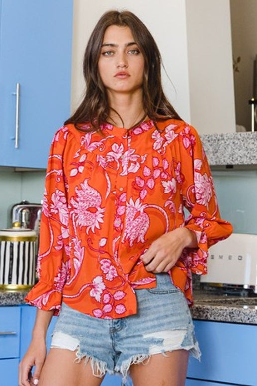 This stylish Chrissy Top features a floral print and is made from lightweight crepe material. The top also boasts a classic crew neck, elegant 3/4 bell sleeves, and a button-up front with charming ruffled details. Perfect for adding a touch of femininity to any outfit.