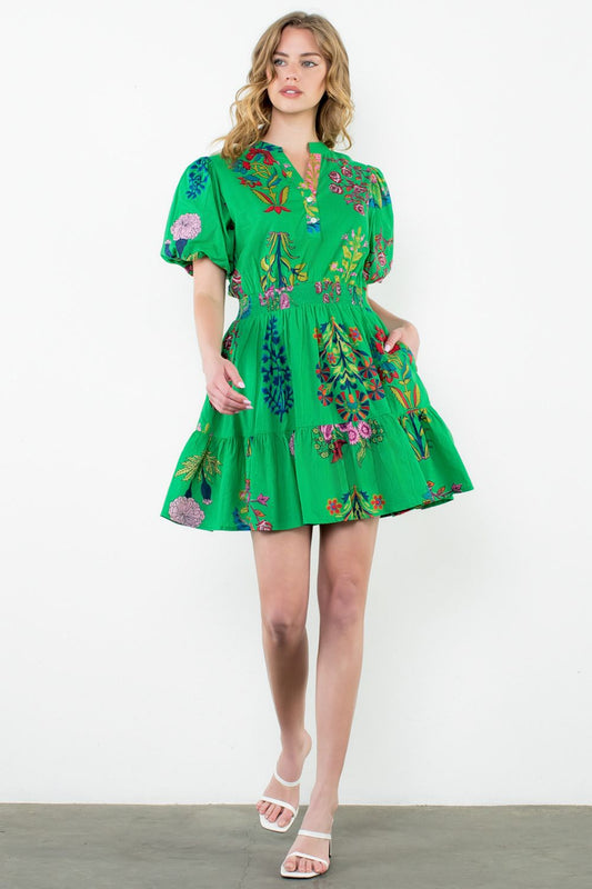 Woman wearing a green embroidered dress on a white background