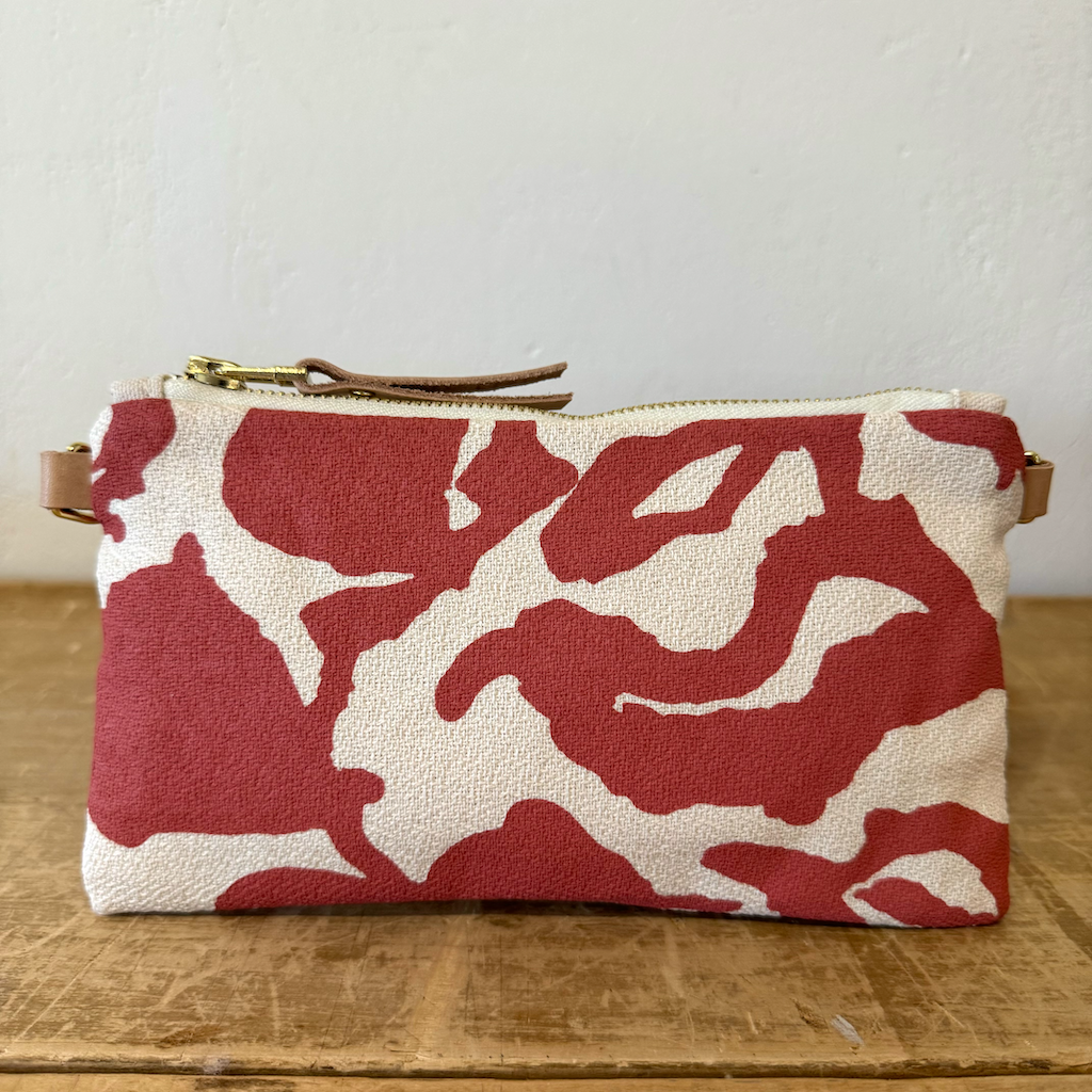 Red and white floral patterned pouch on a wooden surface with a neutral background