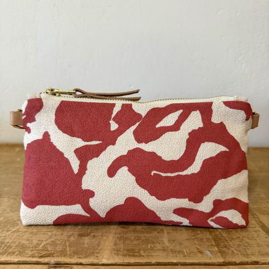 Red and white floral patterned pouch on a wooden surface with a neutral background