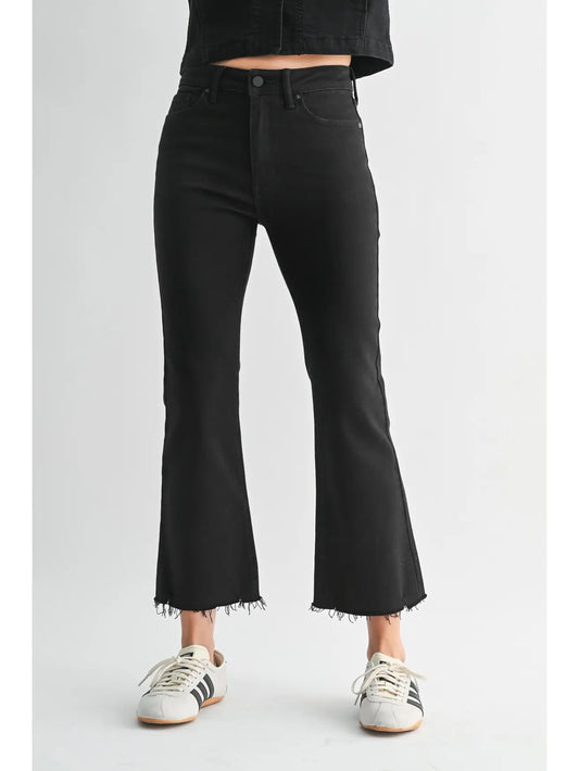 Person wearing black flared jeans on a white background