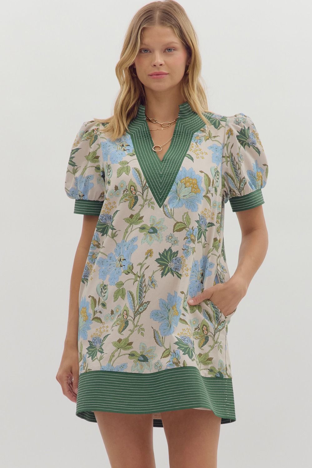 Woman wearing a floral dress with green accents on a white background