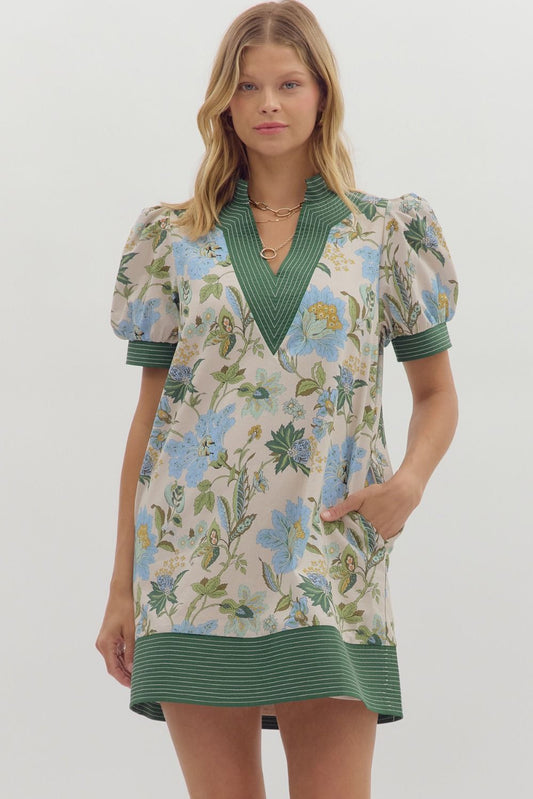 Woman wearing a floral dress with green accents on a white background