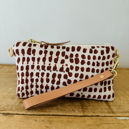 Patterned pouch with a brown strap on a wooden surface